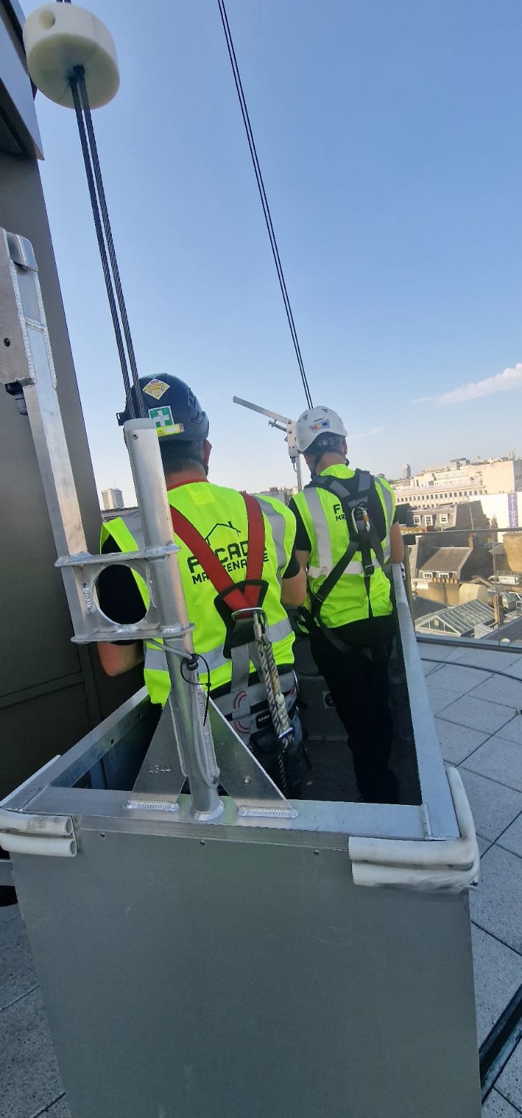 Facade Maintenance crew working from a cradle above the London skyline