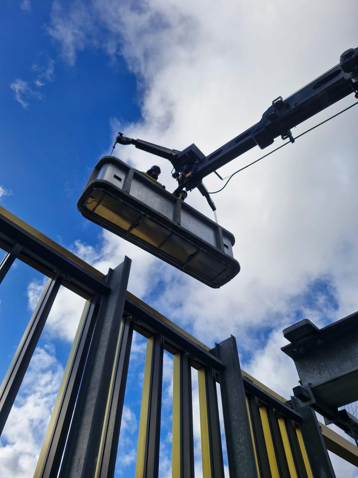 Crew working from a MEWP basket against a blue sky