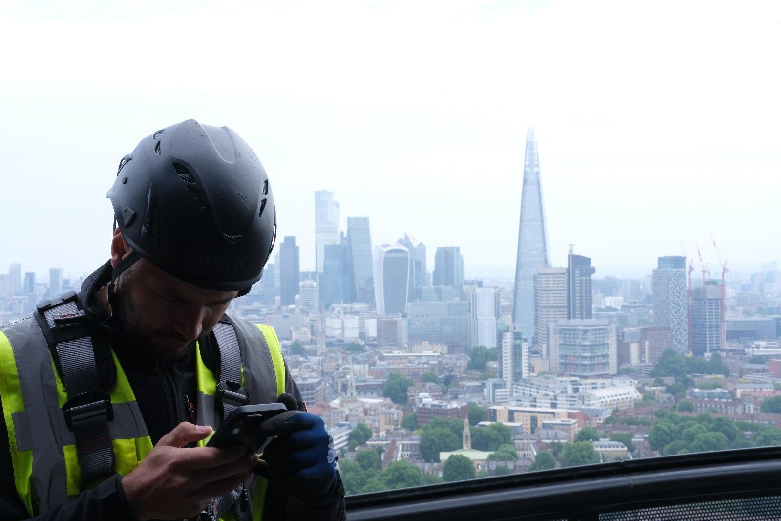 Technician surveying at height above the City of London skyline